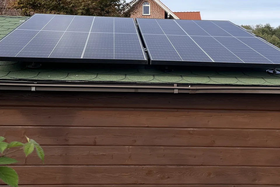 Zwei Solarmodule auf dem flachen Dach eines Holzgebäudes.