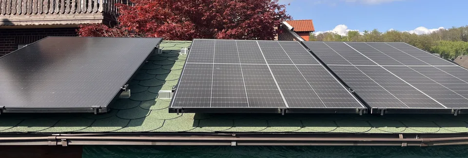Mehrere Solarmodule auf einem Dach, seitlich mit sichtbaren Halterungen aufgenommen.