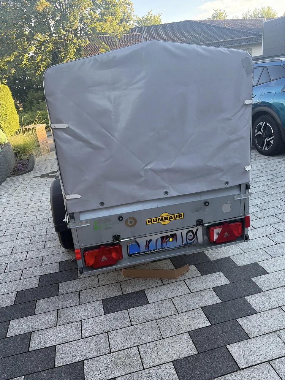 Rückseite des Humbaur-Anhängers mit geschlossener grauer Plane, Heckklappe und Rückleuchten.